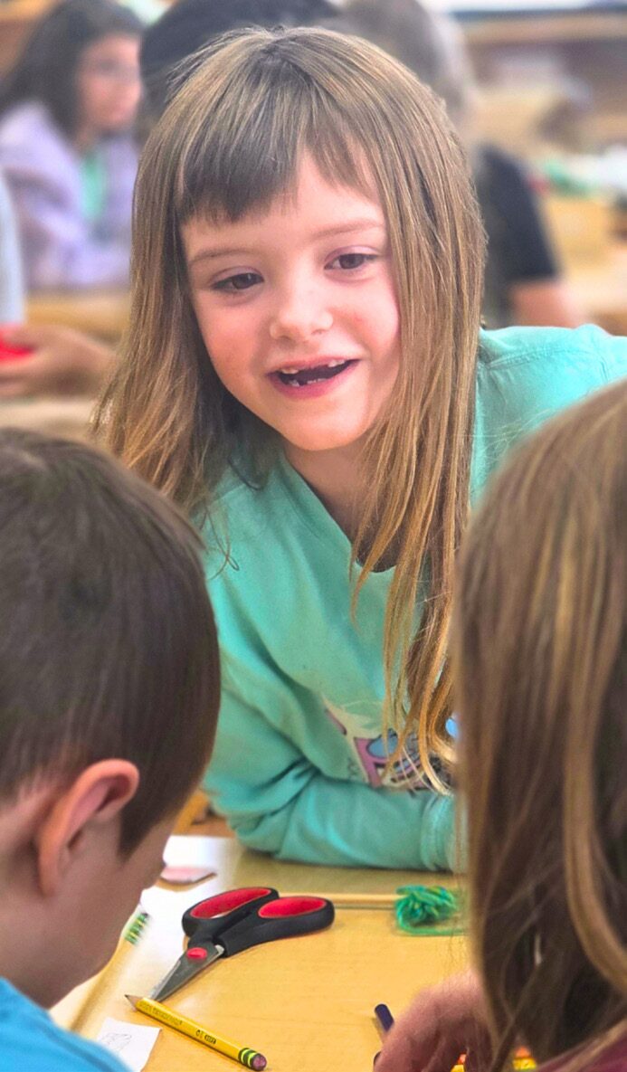 An Elementary student works with classmates at a table.